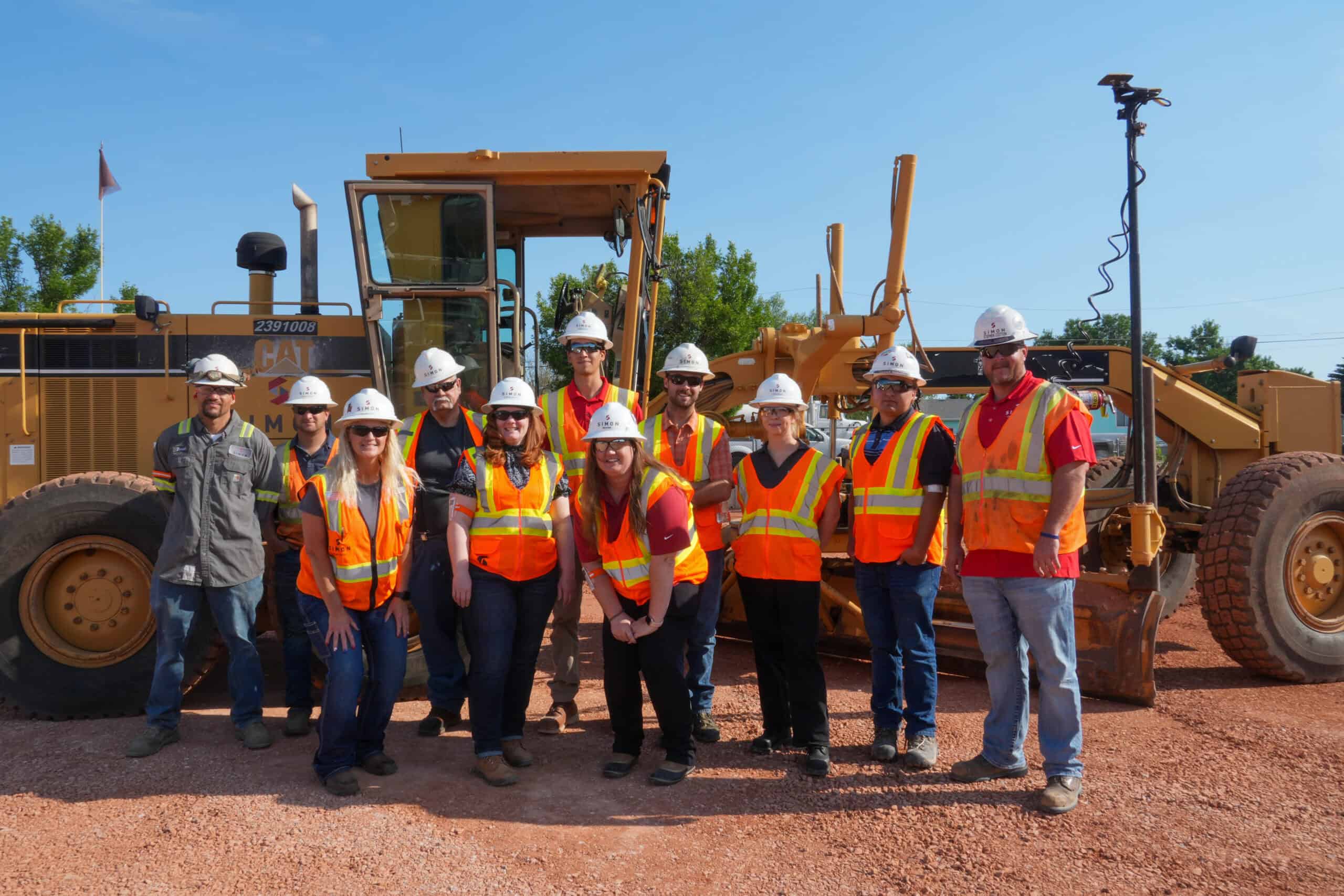 Simon Team standing outside in front of heavy machinery.