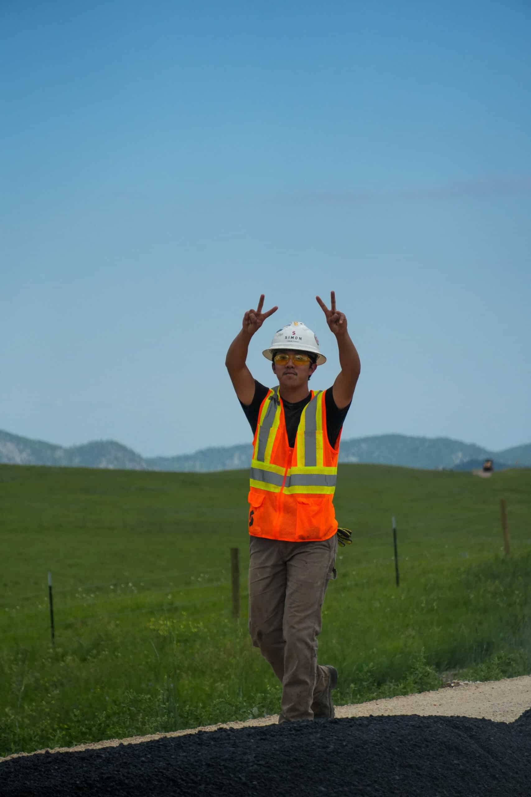 Simon worker in vest and hard hat giving peace sign.
