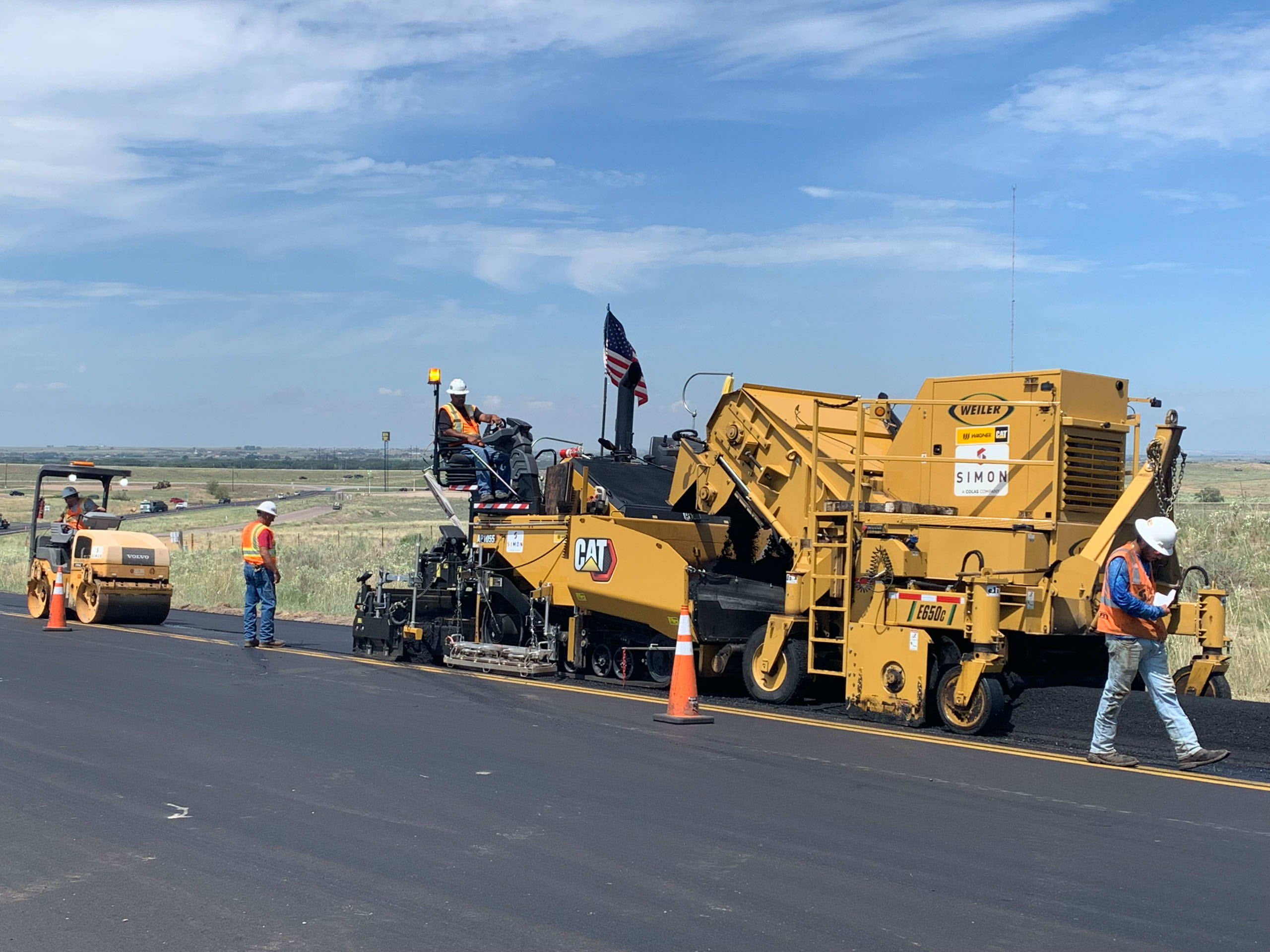 Construction workers using heavy machinery for road paving