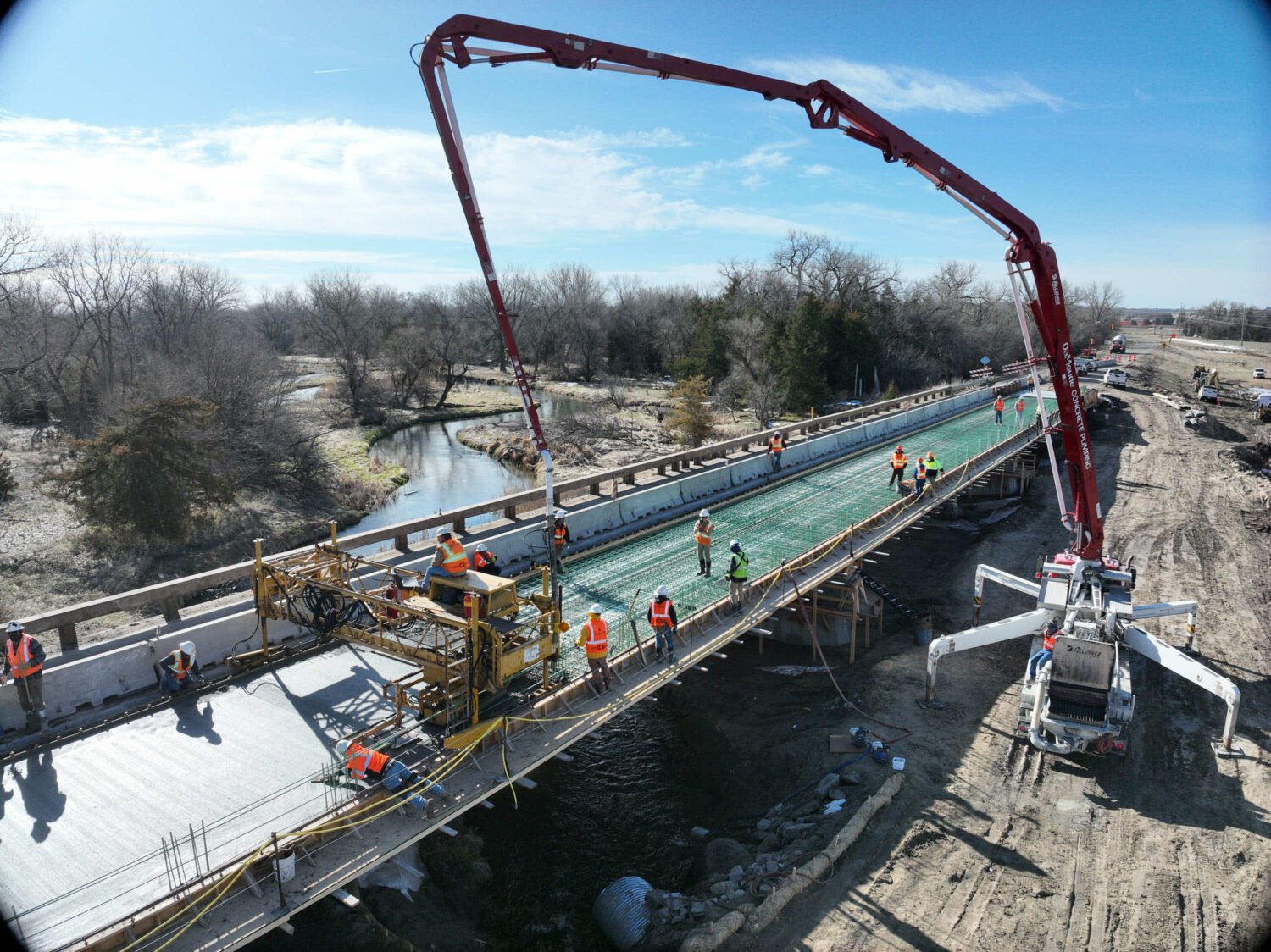 Construction workers pouring concrete on a bridge using a pump truck.